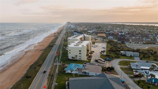 aerial view at dusk with a water view and a view of the beach