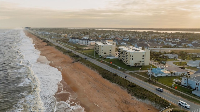 aerial view at dusk with a view of the beach and a water view