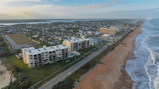 aerial view at dusk with a water view and a beach view