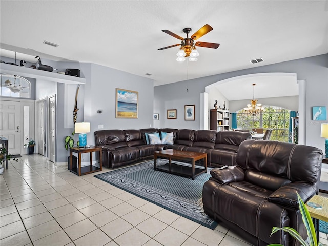 tiled living room with ceiling fan with notable chandelier and lofted ceiling