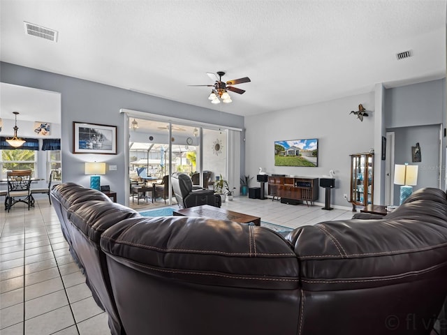 living room featuring ceiling fan, light tile patterned flooring, and a textured ceiling