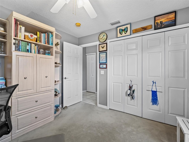 unfurnished office with a textured ceiling, ceiling fan, and light carpet