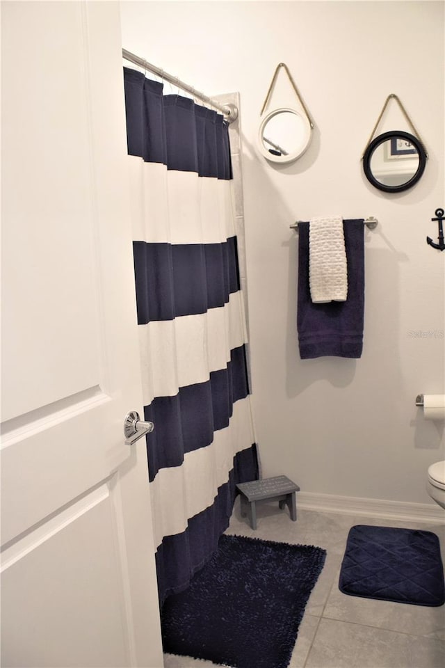 bathroom featuring toilet, a shower with curtain, and tile patterned floors