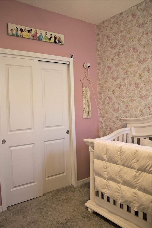 carpeted bedroom with a closet and a crib