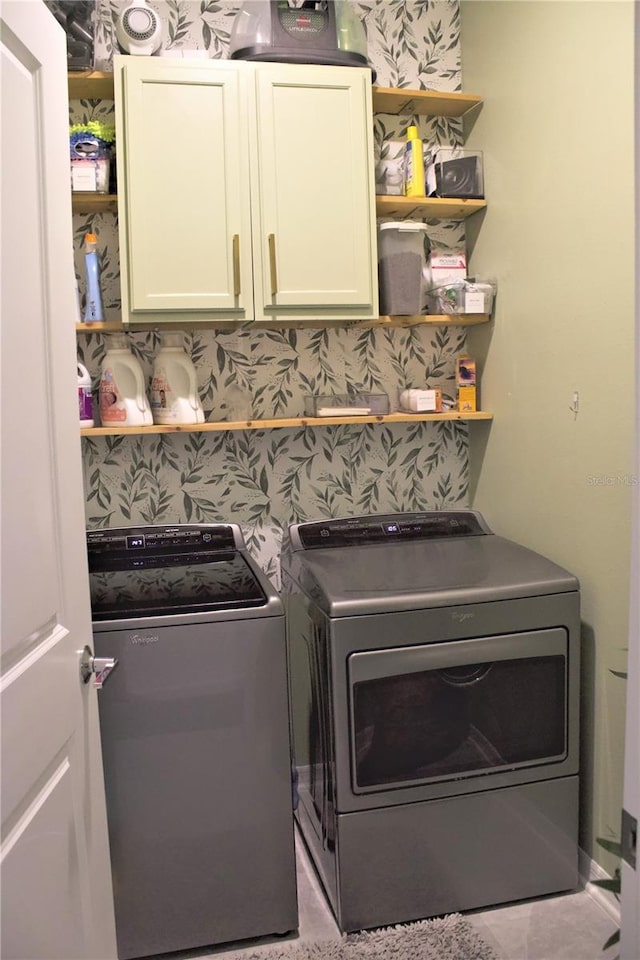 clothes washing area with cabinets and separate washer and dryer