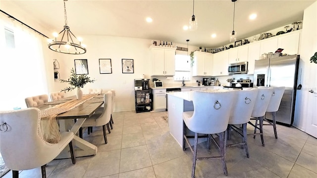 kitchen featuring stainless steel appliances, sink, white cabinets, a kitchen island, and hanging light fixtures