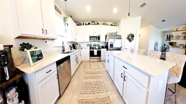 kitchen with hanging light fixtures, stainless steel appliances, a kitchen island, a kitchen breakfast bar, and white cabinets