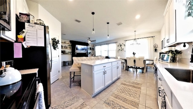 kitchen with ceiling fan, a center island, hanging light fixtures, a breakfast bar, and white cabinets