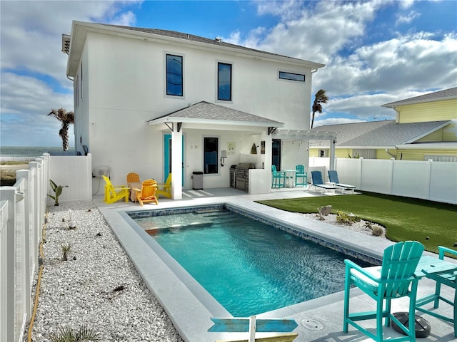 rear view of house with exterior bar, a patio, a fenced in pool, and area for grilling