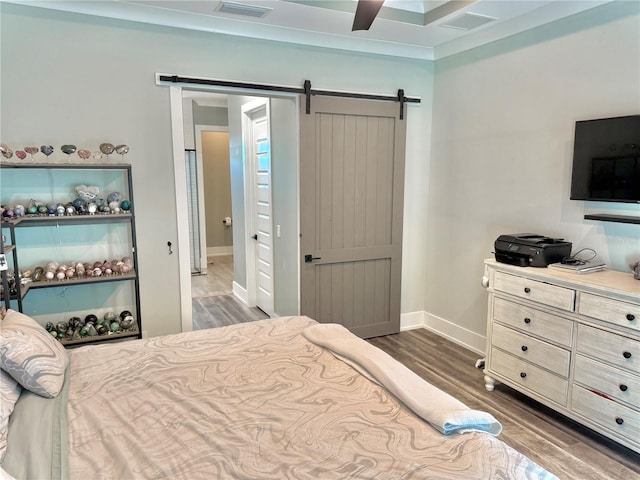 bedroom with a barn door, dark hardwood / wood-style floors, and ceiling fan