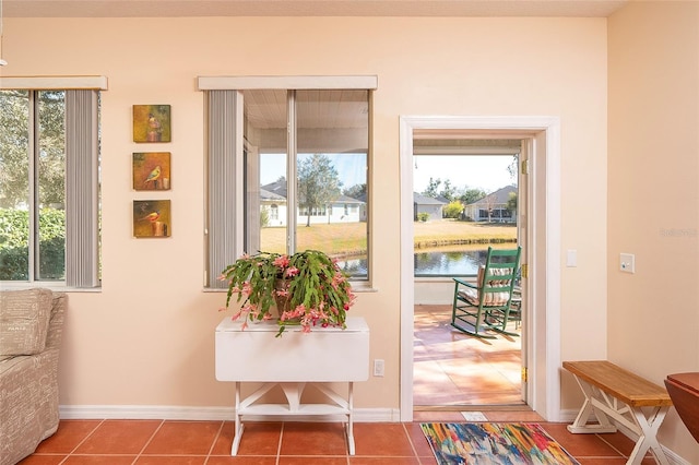 doorway to outside featuring tile patterned flooring, a water view, and a healthy amount of sunlight