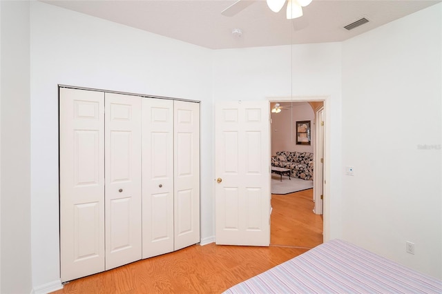 unfurnished bedroom with ceiling fan, a closet, and light wood-type flooring