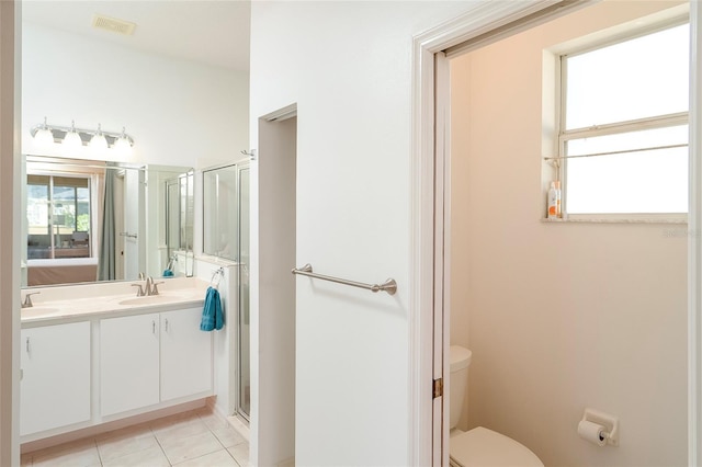 bathroom with tile patterned flooring, vanity, an enclosed shower, and toilet