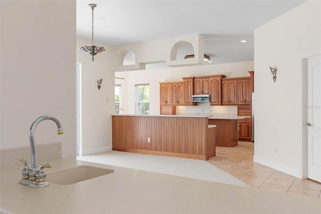 kitchen with sink, hanging light fixtures, light tile patterned floors, and kitchen peninsula