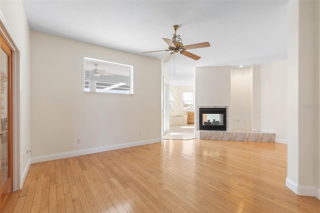 unfurnished living room with a multi sided fireplace, light hardwood / wood-style flooring, and ceiling fan