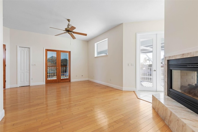 unfurnished living room with ceiling fan, french doors, and light wood-type flooring