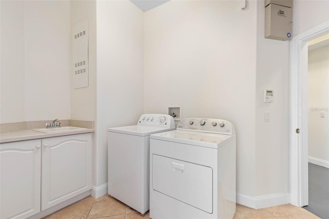 laundry room featuring light tile patterned flooring, sink, cabinets, and washing machine and clothes dryer