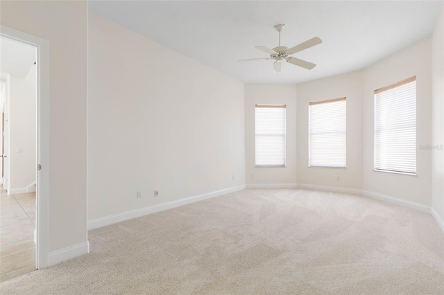 carpeted empty room with ceiling fan and plenty of natural light