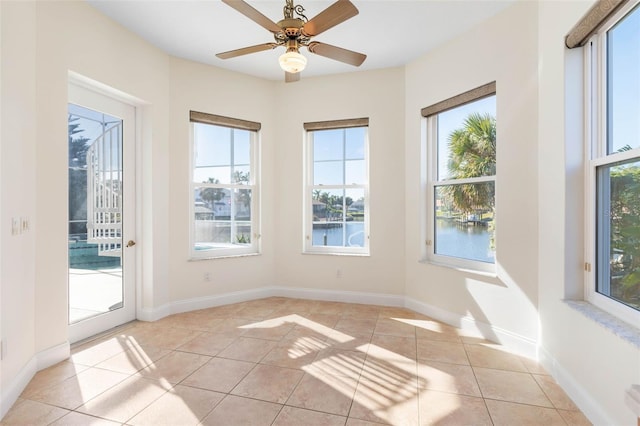 unfurnished sunroom with ceiling fan, a water view, and plenty of natural light