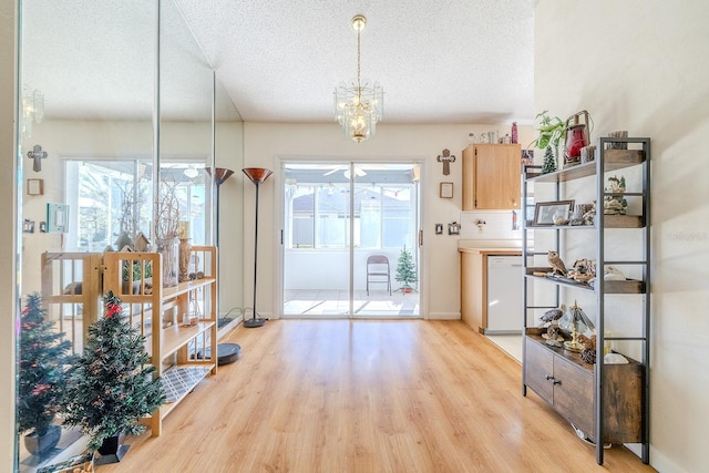 interior space with an inviting chandelier, a textured ceiling, and light wood-type flooring