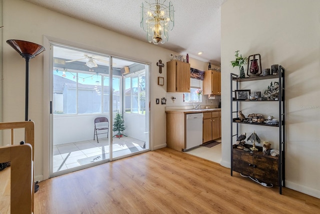 kitchen with light wood-type flooring, ceiling fan with notable chandelier, a textured ceiling, white dishwasher, and hanging light fixtures