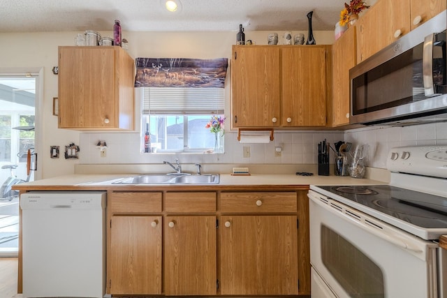 kitchen with a healthy amount of sunlight, sink, white appliances, and a textured ceiling