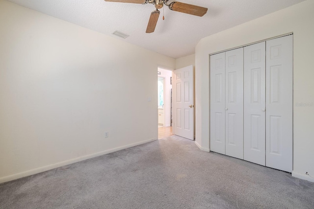 unfurnished bedroom with a textured ceiling, a closet, ceiling fan, and light colored carpet