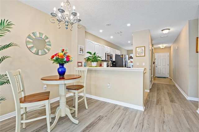 kitchen featuring light hardwood / wood-style floors, white cabinetry, kitchen peninsula, and appliances with stainless steel finishes