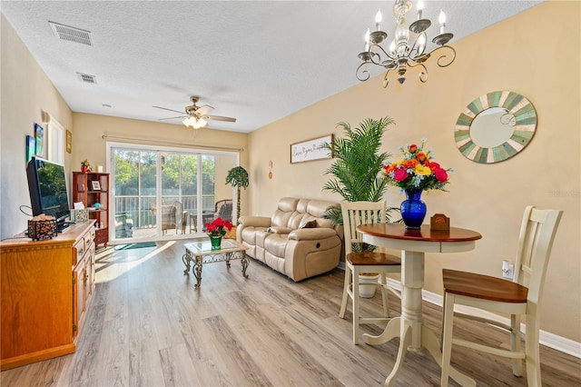 living room with light hardwood / wood-style flooring, ceiling fan with notable chandelier, and a textured ceiling