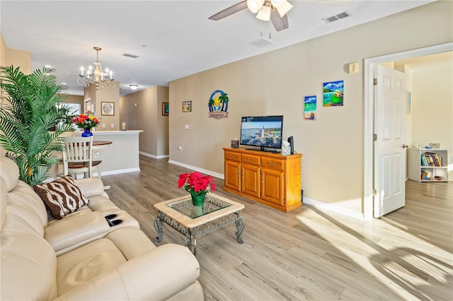 living room featuring ceiling fan with notable chandelier and light hardwood / wood-style flooring