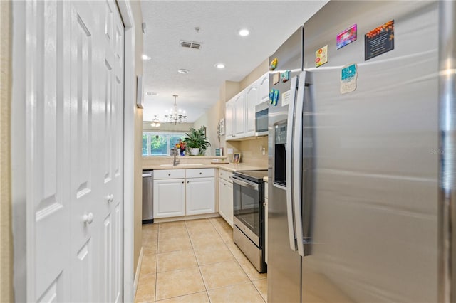 kitchen featuring white cabinetry, stainless steel appliances, an inviting chandelier, pendant lighting, and light tile patterned floors