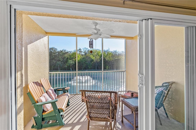 sunroom / solarium with ceiling fan and a water view