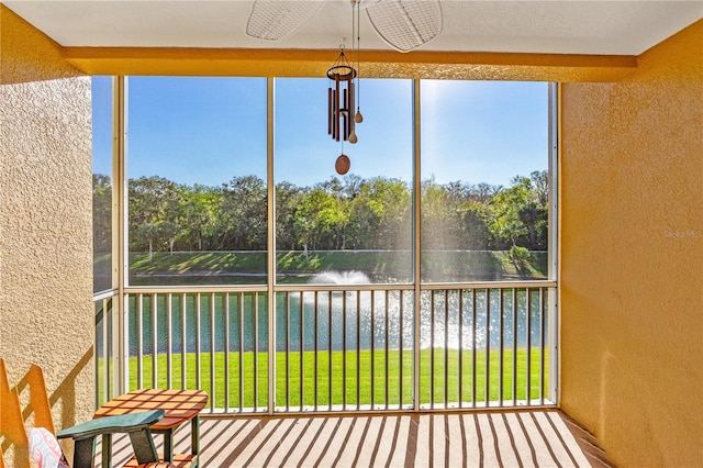 unfurnished sunroom with ceiling fan and a water view