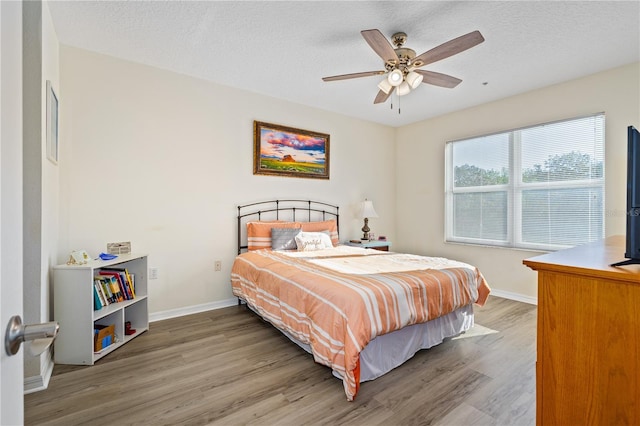 bedroom featuring hardwood / wood-style floors, ceiling fan, and a textured ceiling