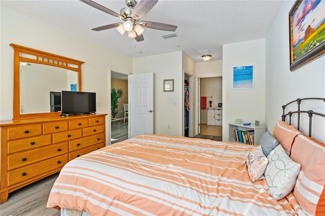 bedroom with a textured ceiling, light wood-type flooring, a closet, and ceiling fan