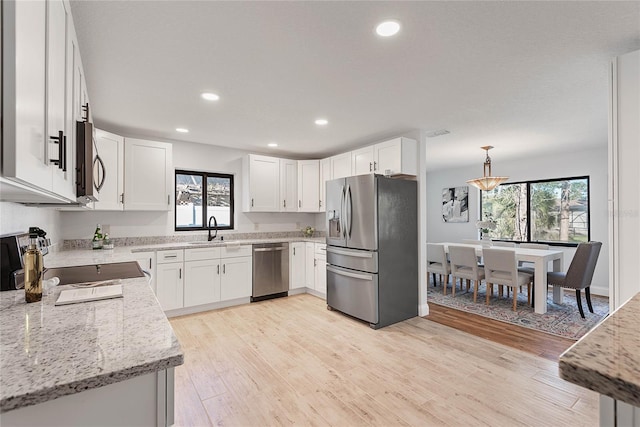 kitchen with light stone countertops, sink, pendant lighting, white cabinets, and appliances with stainless steel finishes