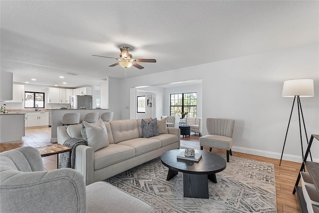 living room with light hardwood / wood-style flooring, ceiling fan, and sink