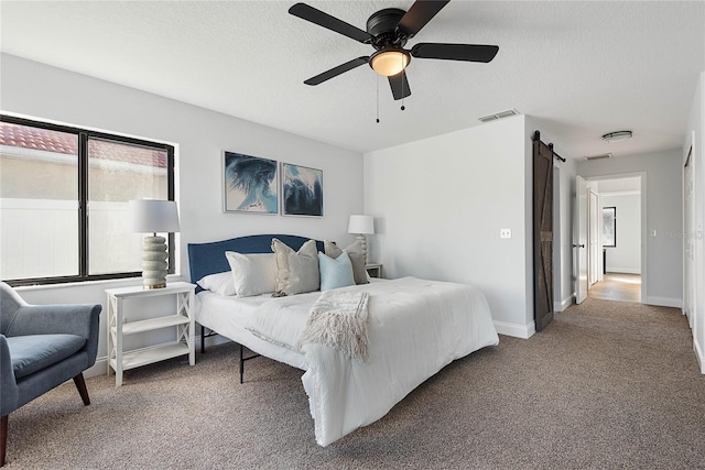 carpeted bedroom featuring ceiling fan and a barn door