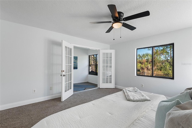 carpeted bedroom with multiple windows, french doors, a textured ceiling, and ceiling fan