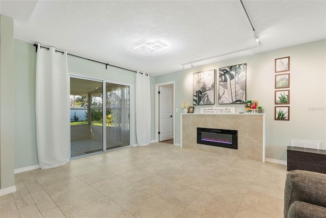 living room featuring rail lighting and a tiled fireplace