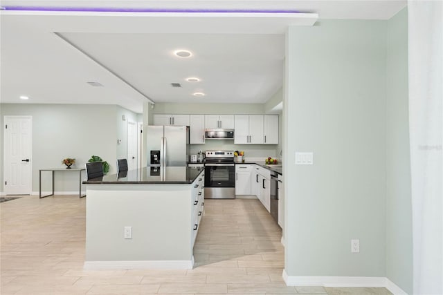 kitchen featuring sink, white cabinets, dark stone countertops, a kitchen island, and appliances with stainless steel finishes