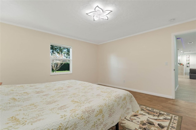 bedroom featuring hardwood / wood-style floors, crown molding, and a textured ceiling