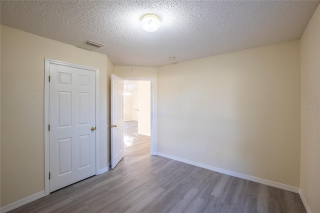 empty room featuring a textured ceiling and light hardwood / wood-style flooring