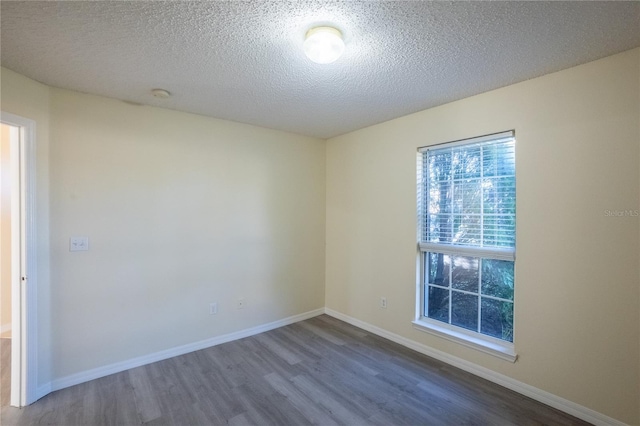 unfurnished room with wood-type flooring and a textured ceiling