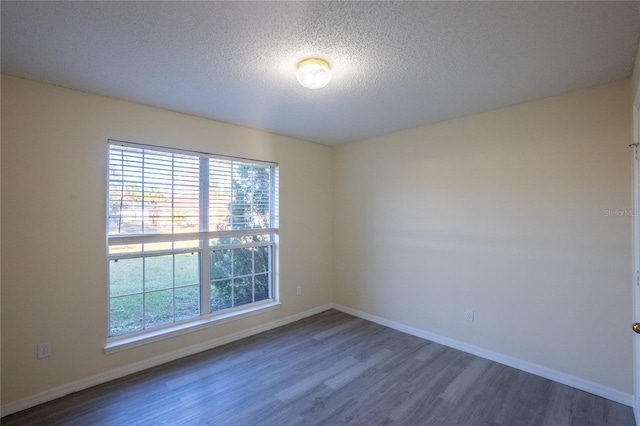 empty room featuring dark wood-type flooring and a textured ceiling