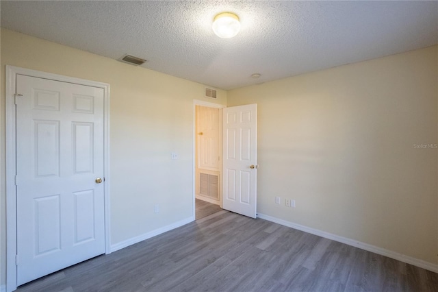 unfurnished bedroom featuring a closet, a textured ceiling, and hardwood / wood-style flooring