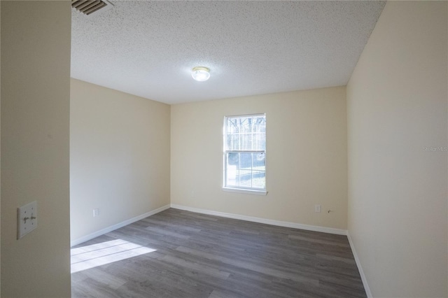 spare room featuring dark hardwood / wood-style floors and a textured ceiling