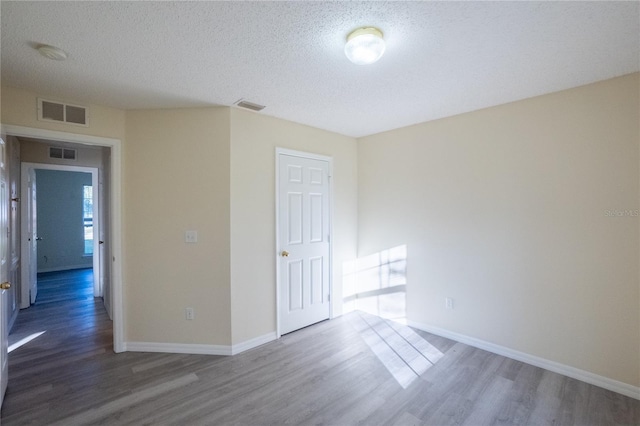 spare room featuring dark hardwood / wood-style floors and a textured ceiling