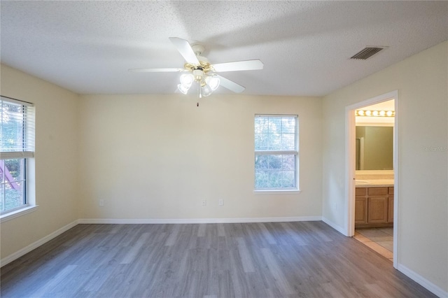 empty room with hardwood / wood-style flooring, ceiling fan, and a textured ceiling