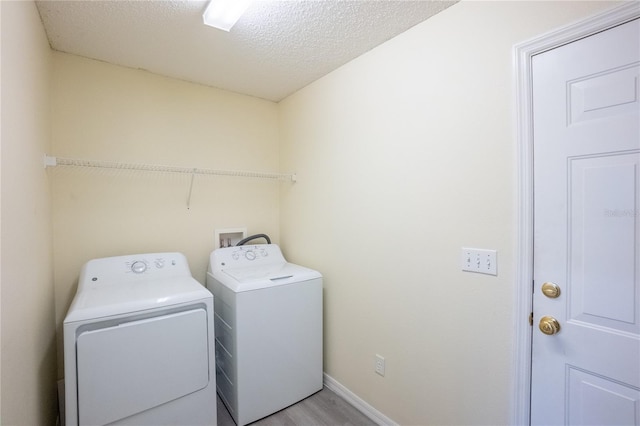 washroom with washer and clothes dryer, light hardwood / wood-style floors, and a textured ceiling